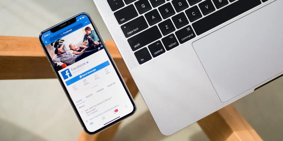 Facebook on mobile app next to laptop